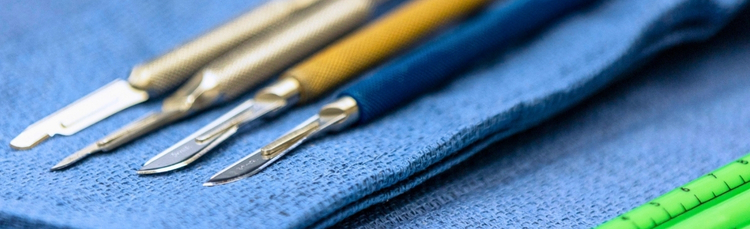 4 scalpels resting on a blue surgical drape